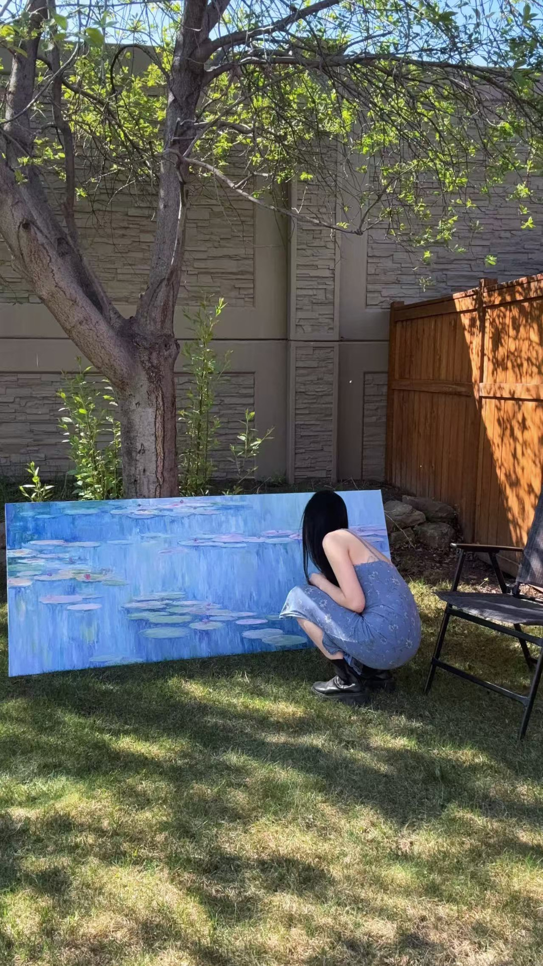 Estelle Yu painting a large water-lily canvas outdoors